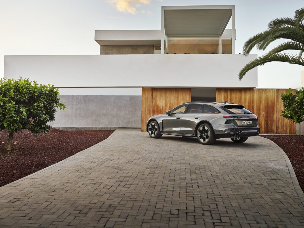 Audi A6 allroad (plateau grey metallic) rear view in front of modern architecture (static shot).